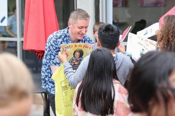 Shenandoah University Children's Literature Conference speaker John Schu signs books for schoolchildren at a Rally for Reading to kick off the virtual/in-person conference in April.